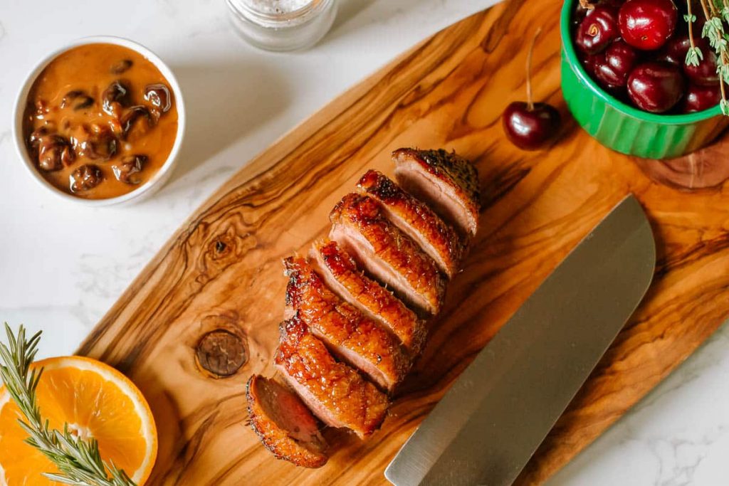 Duck Breast With Cherries on a chopping board